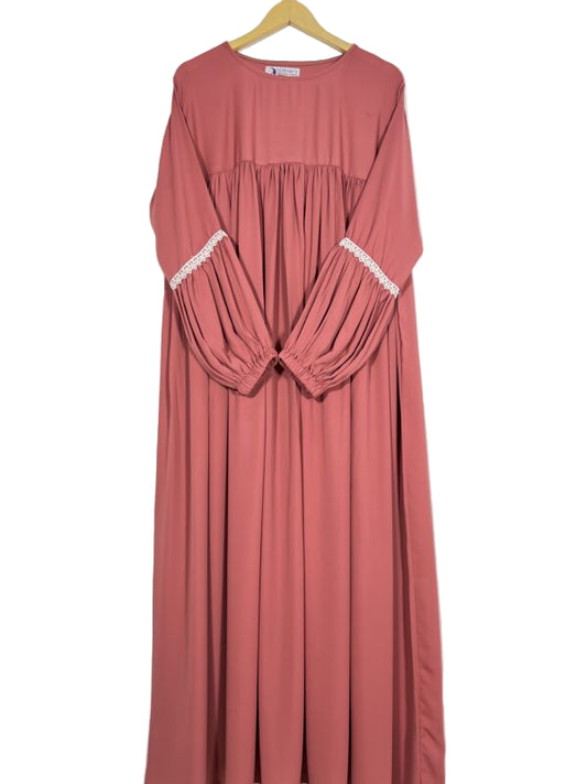Pink dress with lace trim on a hanger against a white background
