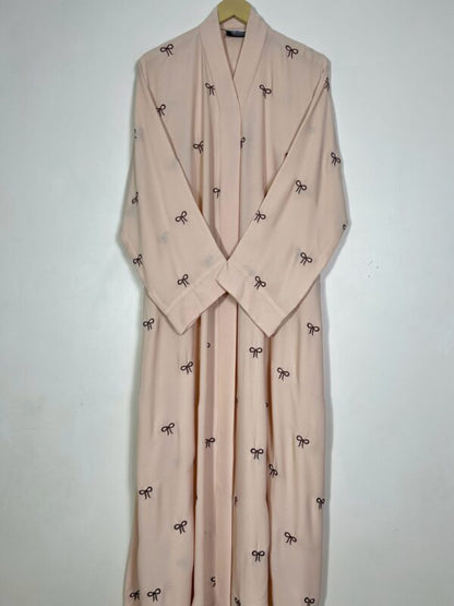 Beige robe with black bow patterns on a white background